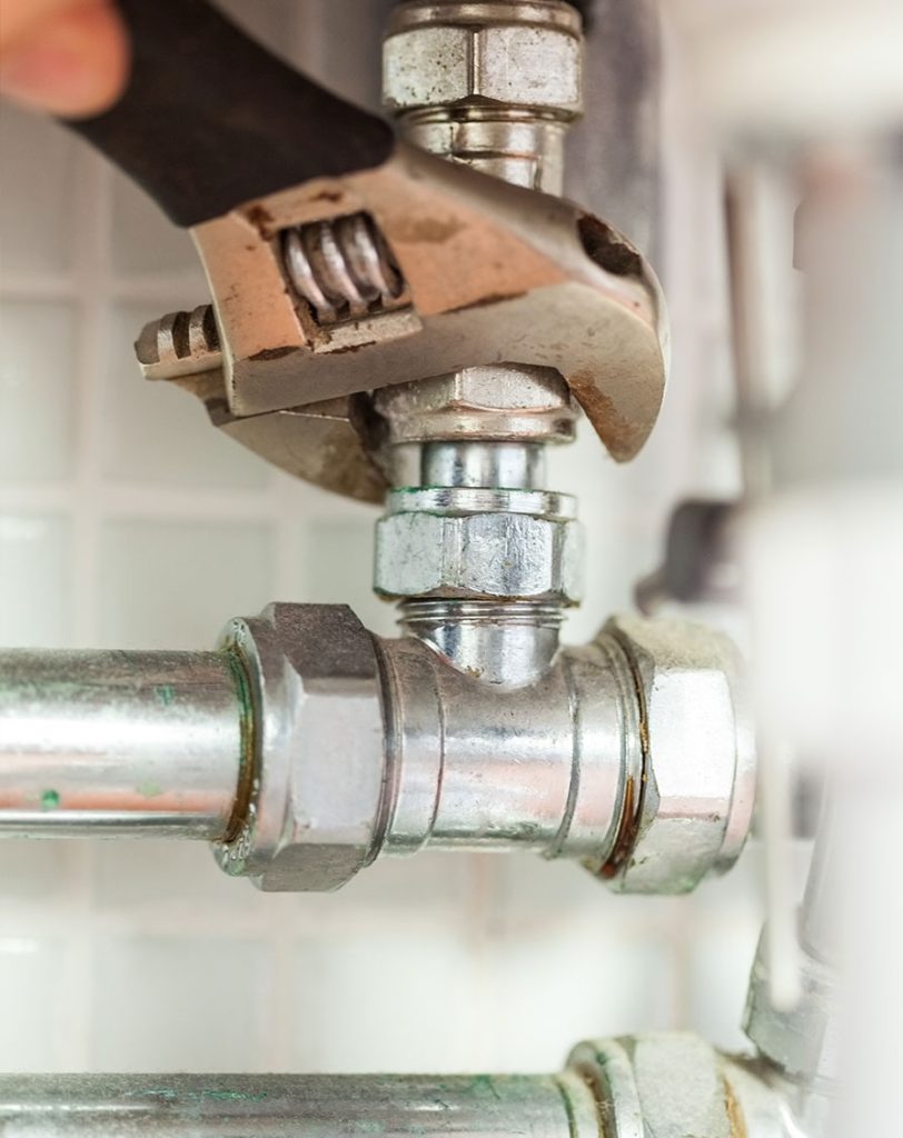 Plumber using an adjustable wrench on metal piping, showcasing plumbing repair work relevant to Clearwater Plumbing and Civil's services.